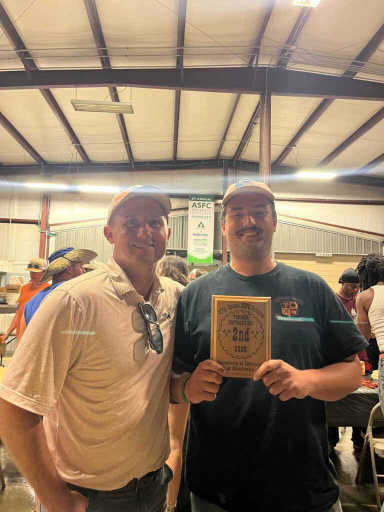 One person holds a plague, and another stands and smiles.