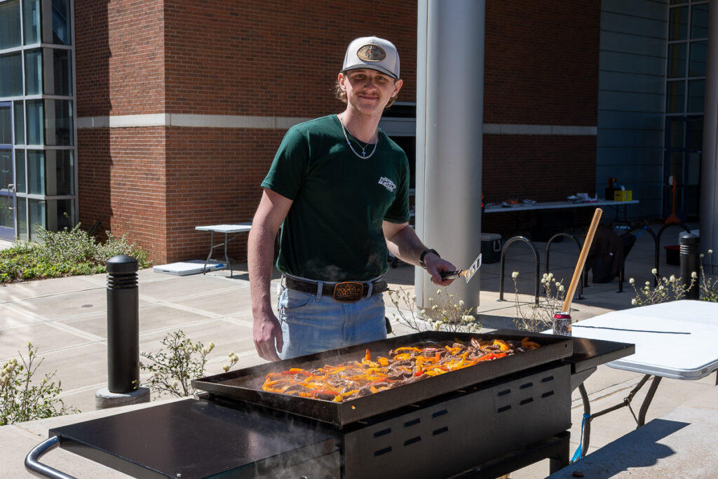 A person grills outside a building on the UT Institute of Agriculture campus.