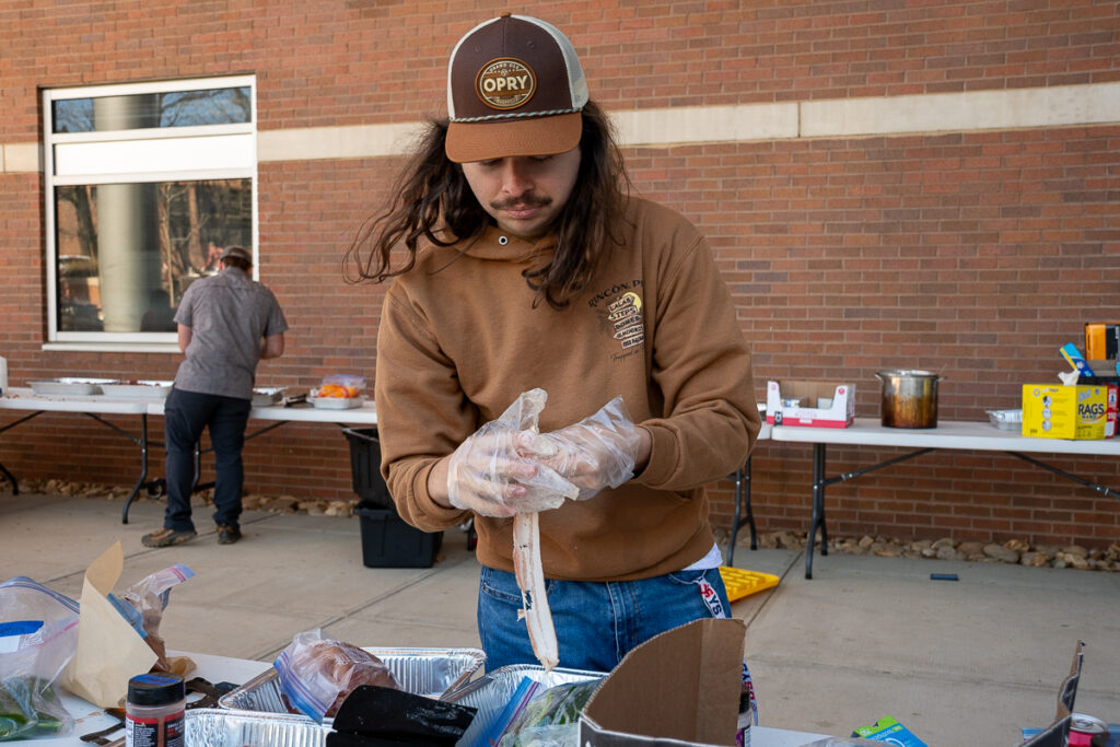 A person holds a piece a of bacon outside building on the UT Institute of Agriculture campus.
