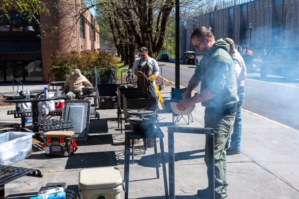 Four people stand beside grills outside a building on the UT Institute of Agriculture campus.