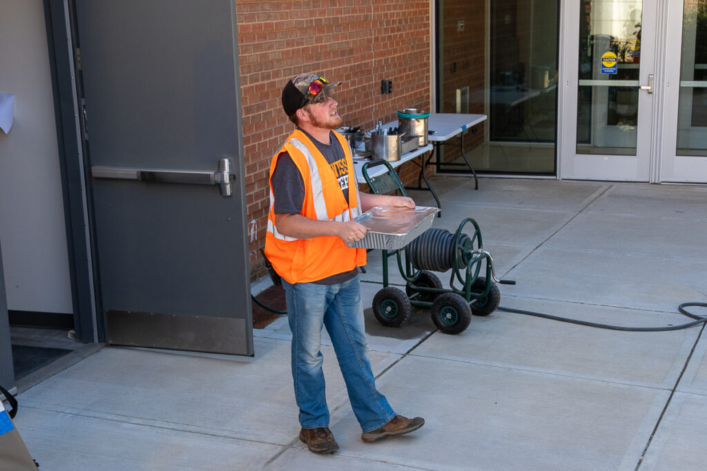 A person holds a pan outside a building on the UT Institute of Agriculture campus.