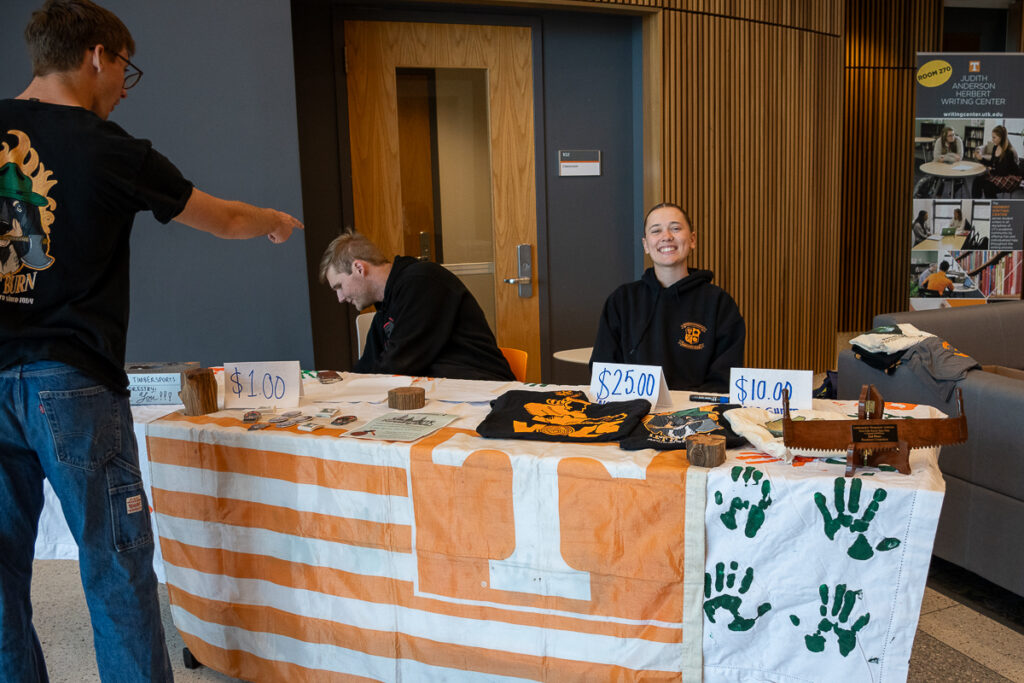 Two people sit and one person stands next to a table in a building on the UT Institute of Agriculture campus.