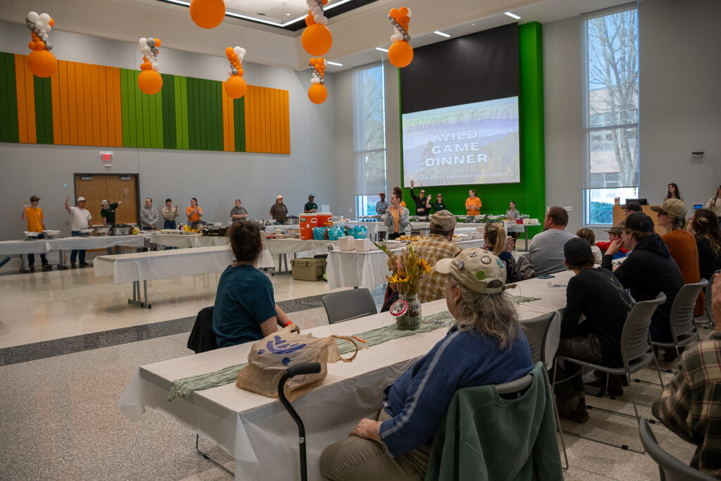 People sit and stand around tables in a building on the UT Institute of Agriculture campus.