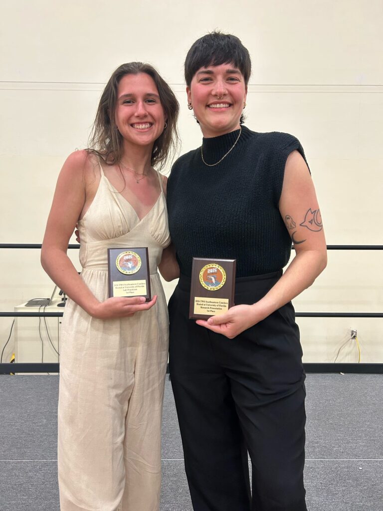 Two people hold plagues at the University of Florida.
