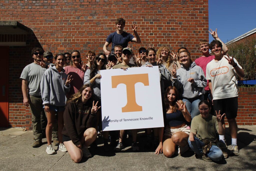 Twenty people pose with a University of Tennessee sign at the University of Florida.