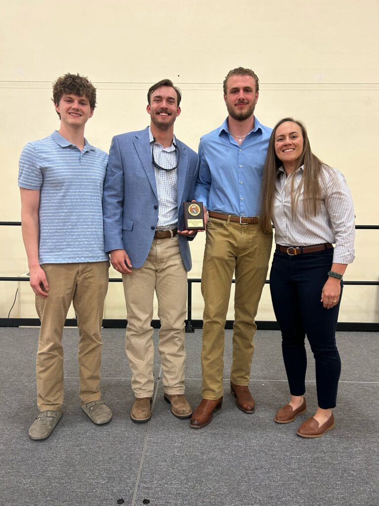 Four people pose on a podium at the University of Florida.