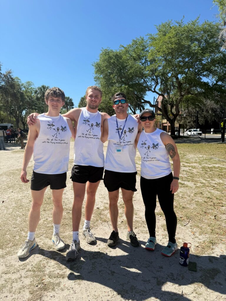 Four people stand with arms on each others' shoulders on the University of Florida campus.