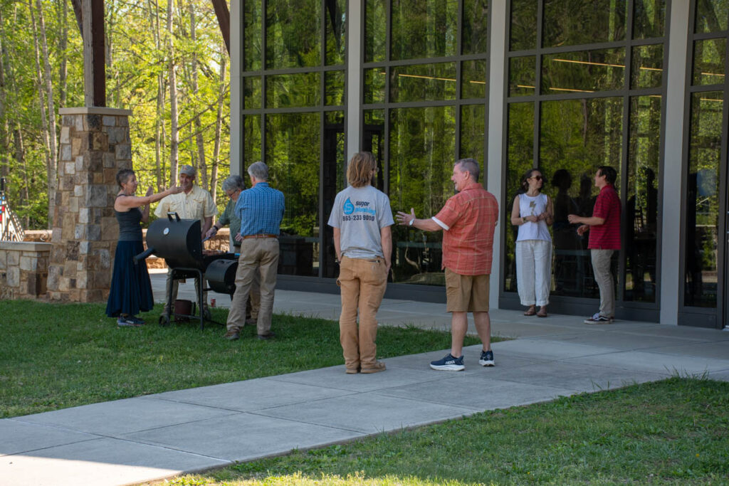 Eight people stand outside the UT Arboretum Auditorium with a grill.