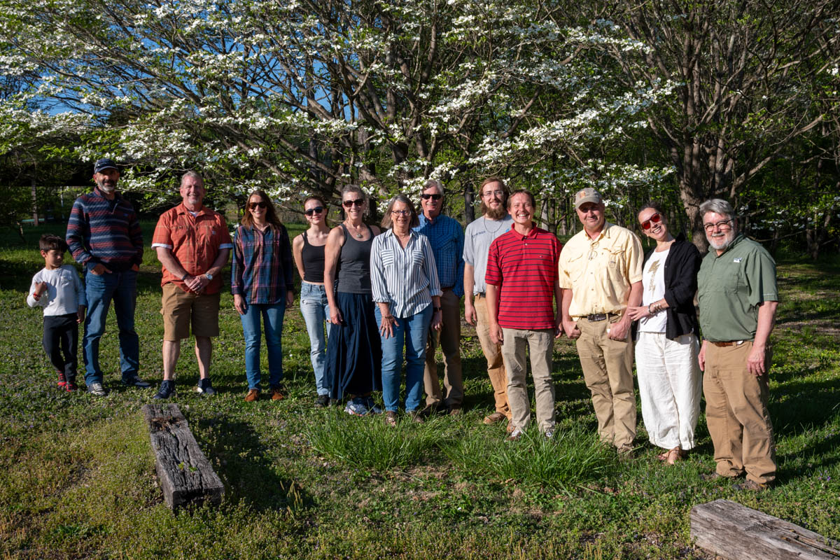 Thirteen people stand and smile in front of a dogwood tree at the UT Arboretum.