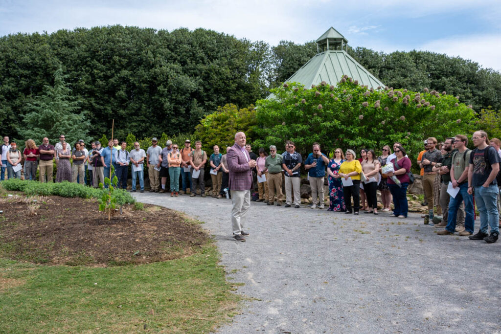 A person speaks to a crowd of people in UT Gardens.