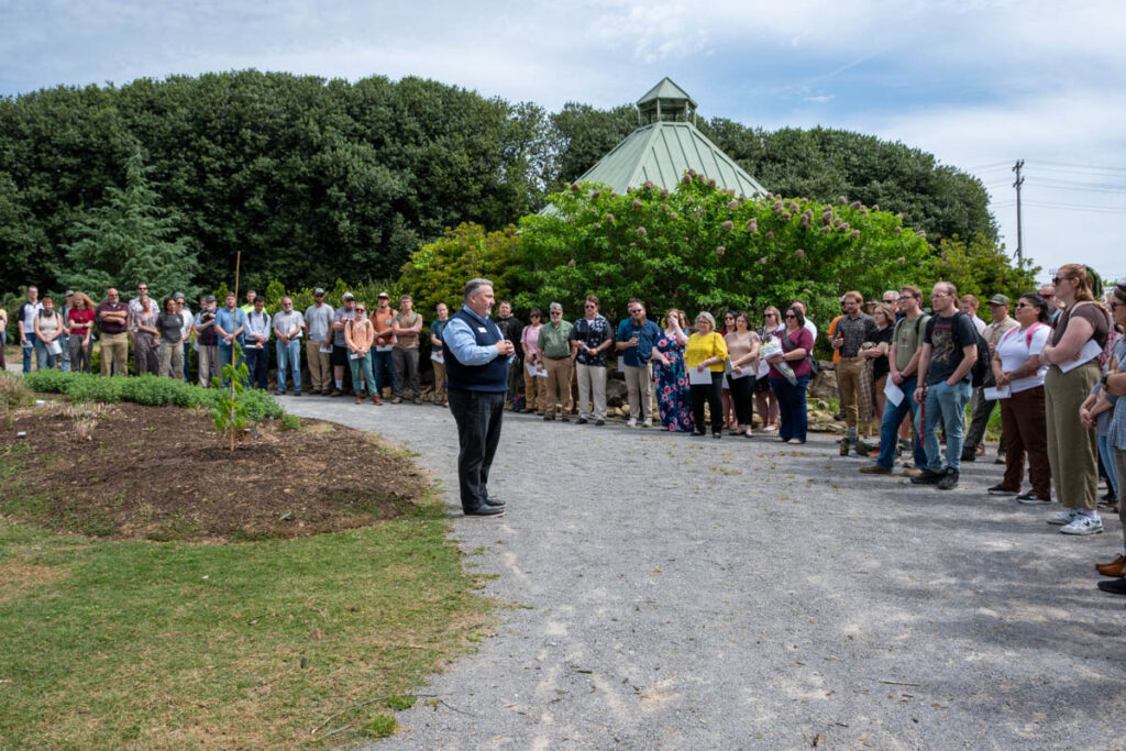 A person speaks to a crowd of people in UT Gardens.