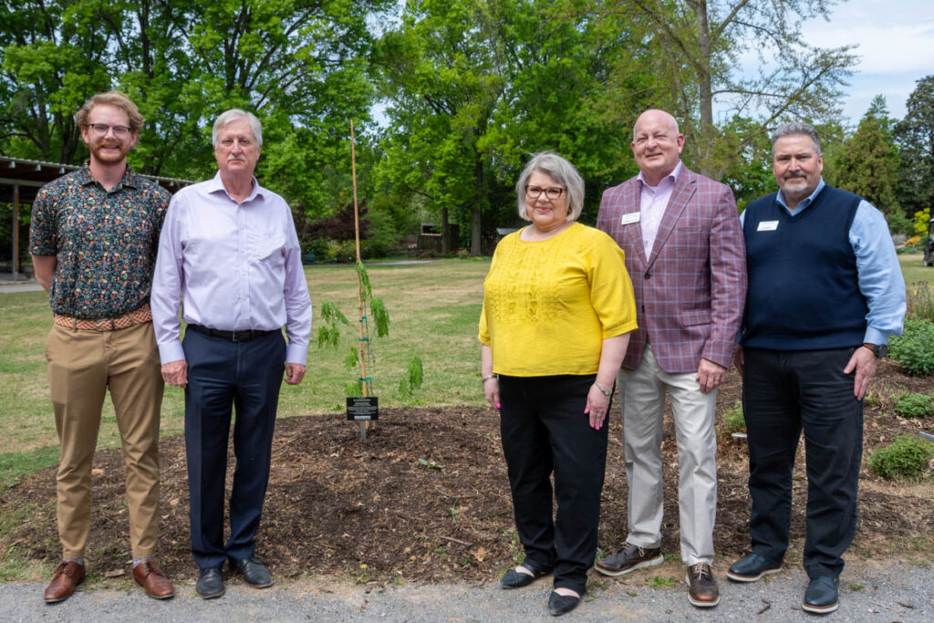 Five people stand beside a white oak tree planting in UT Gardens.