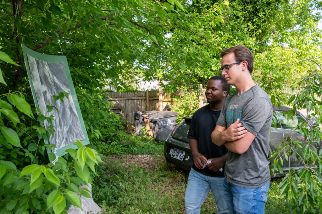 Two people look at a drawing on a tree.