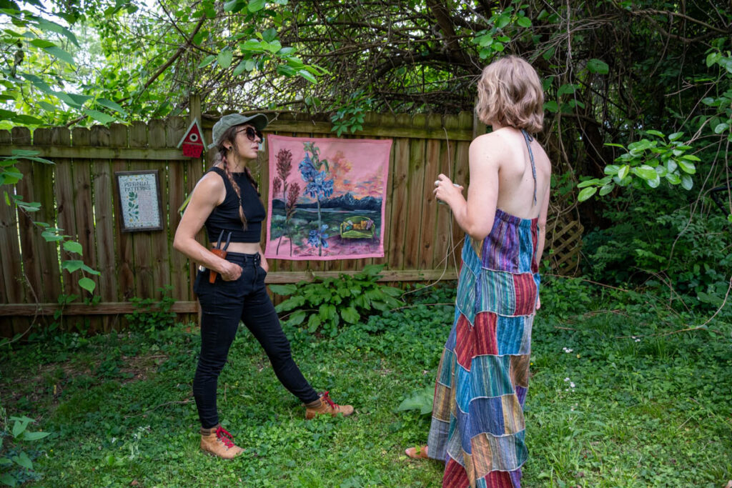 Two people talk in front of a painting.