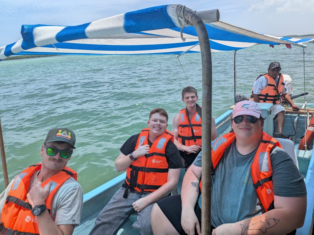 Five people wearing life vests on a boat.