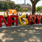 People pose around a sign saying "Nagoya" in Nagoya, Japan.