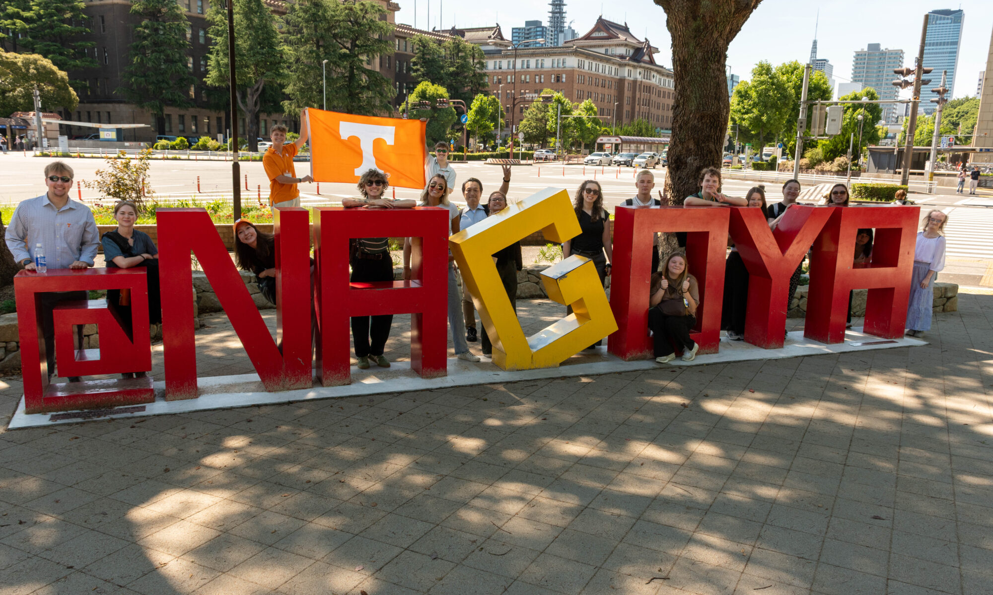 People pose around a sign saying "Nagoya" in Nagoya, Japan.