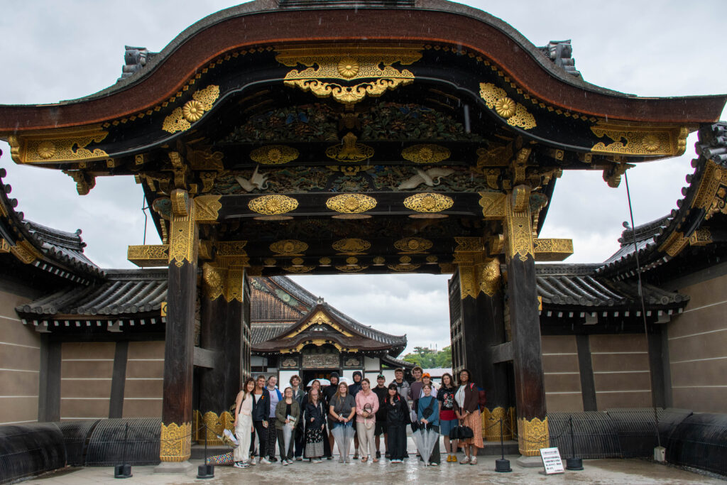People pose under the entrance to the Nijo Castle in Kyoto, Japan.