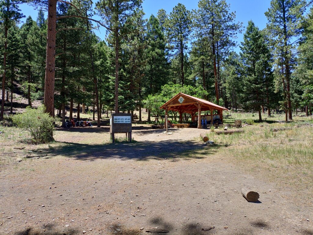 Backpacks sit on ground to the left of a wooden pavilion on the Philmont Scout Ranch in New Mexico.