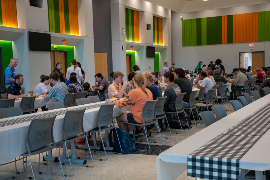 Dozens of people sit at long tables in a building on the UT Institute of Agriculture campus.