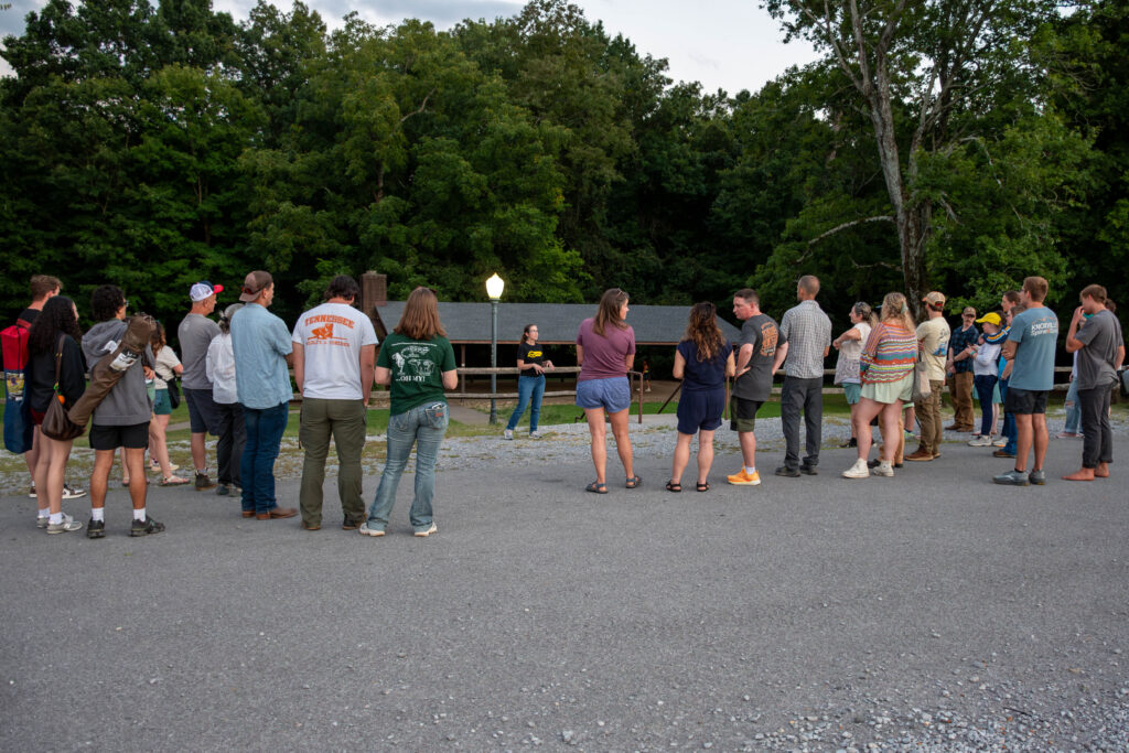 Several people stand around one person speaking in a parking lot on Maryville College campus.