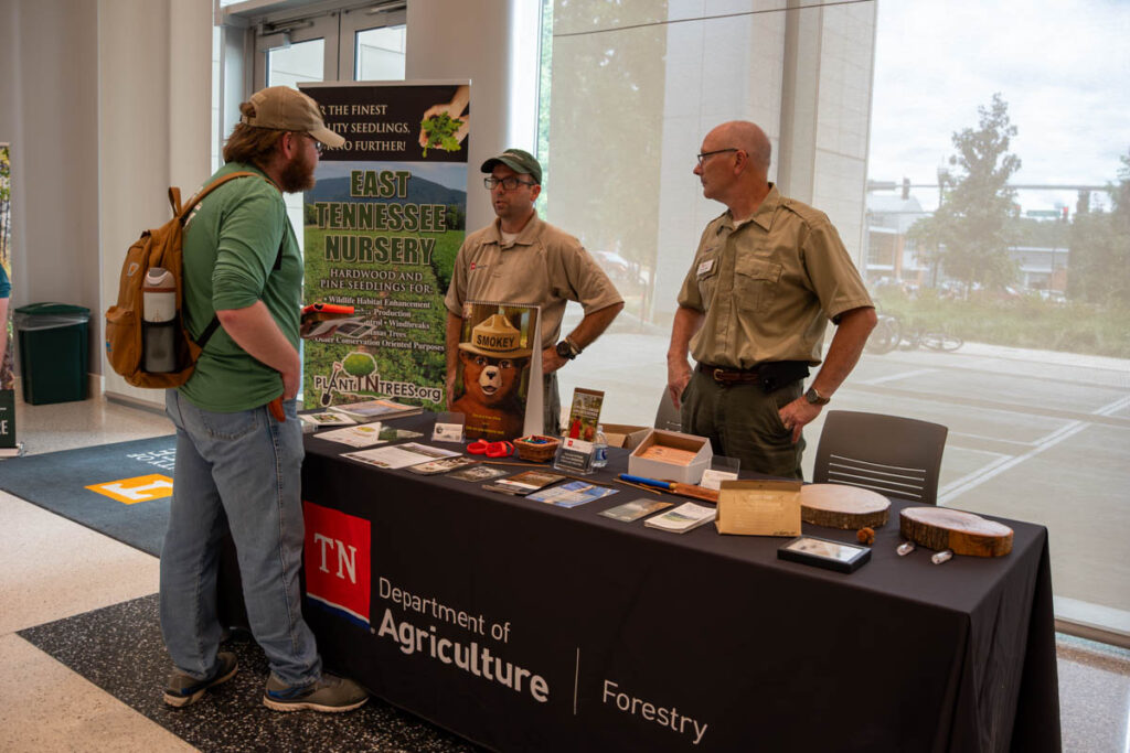 Three people stand and talk around a table in a building on the UT Institute of Agriculture campus.