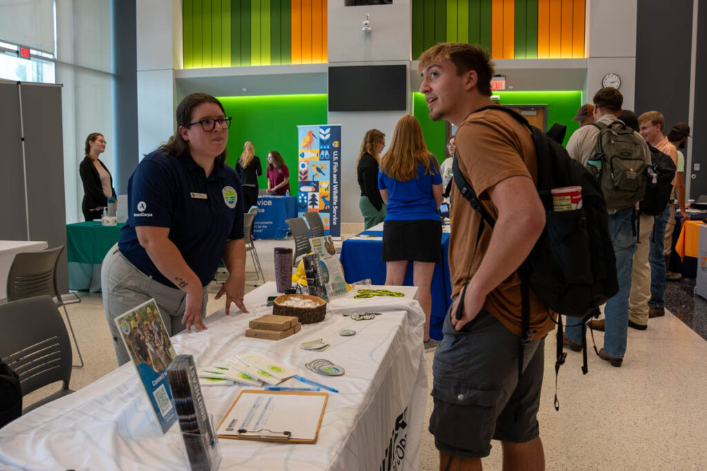 Two people stand and talk around a table in a building on the UT Institute of Agriculture campus.