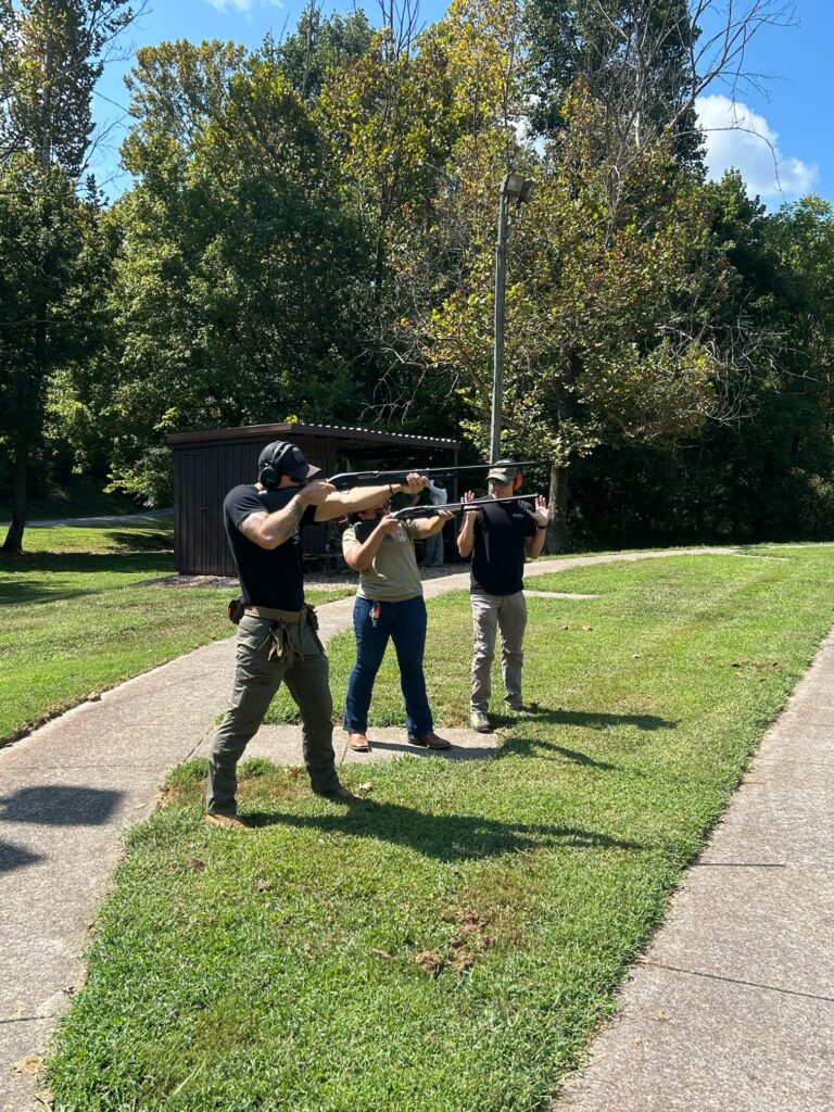 One person shoots a gun while two others stand nearby.
