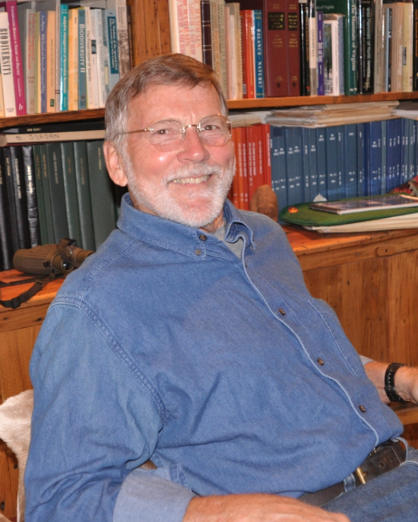 Person wearing glasses sits in library.