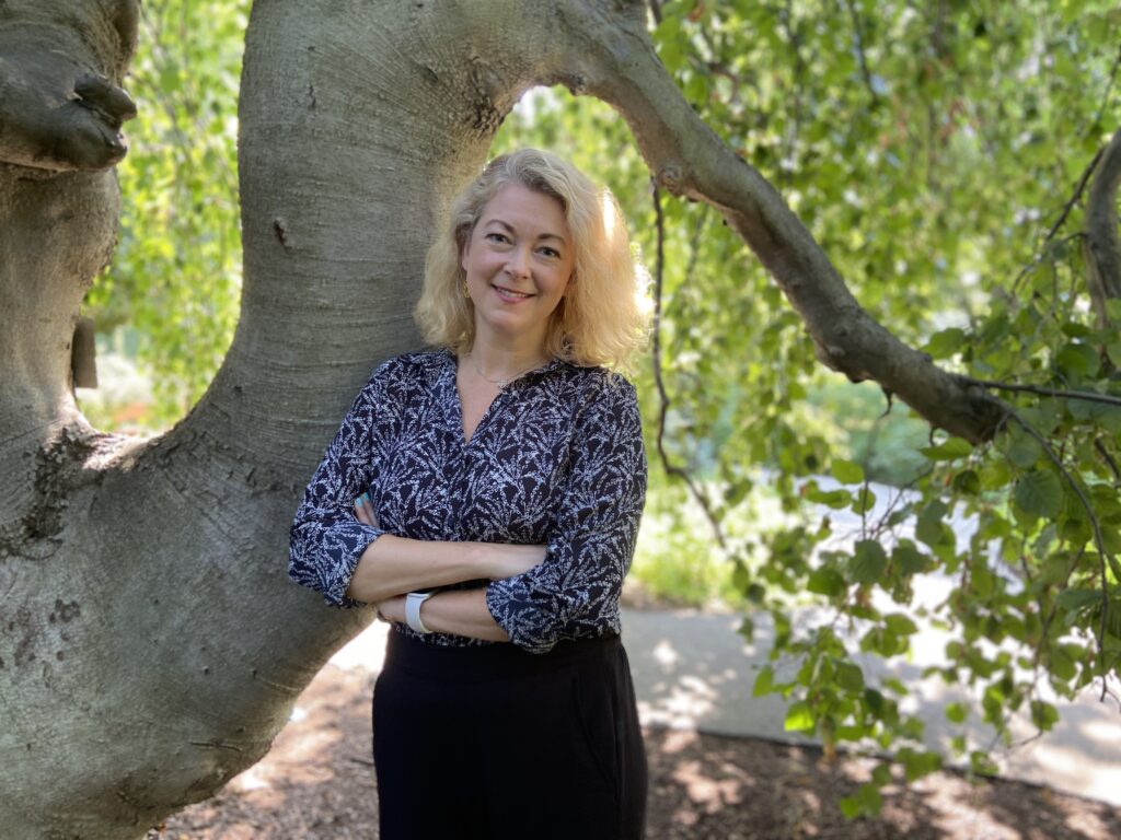 Person stands in front of tree.